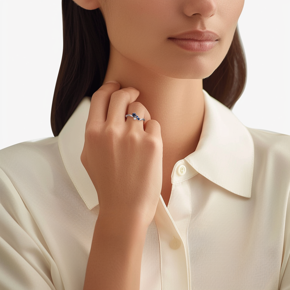 Prsten z bílého zlata s diamantem a modrými safíry na ruce modelky. Luxusní dámský prsten